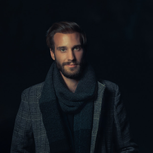 Der Musiker Niklas Vaupel steht vor einem dunklen Hintergrund und schaut in die Kamera